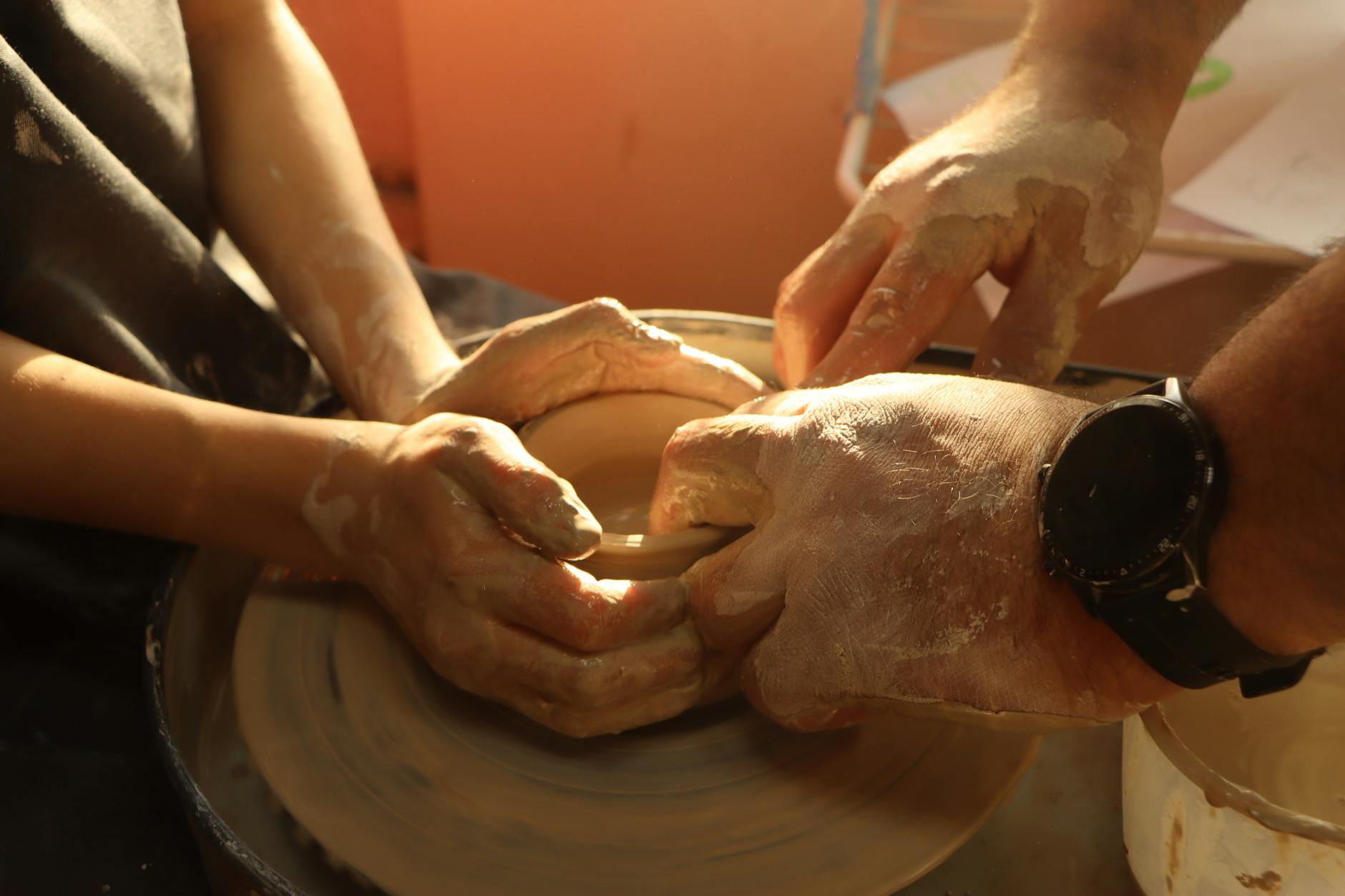 Hands working clay on a pottery wheel in a studio setting