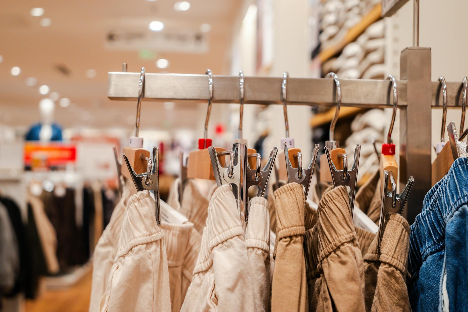 Organized clothing racks in a bright retail store showing various garments hanging neatly