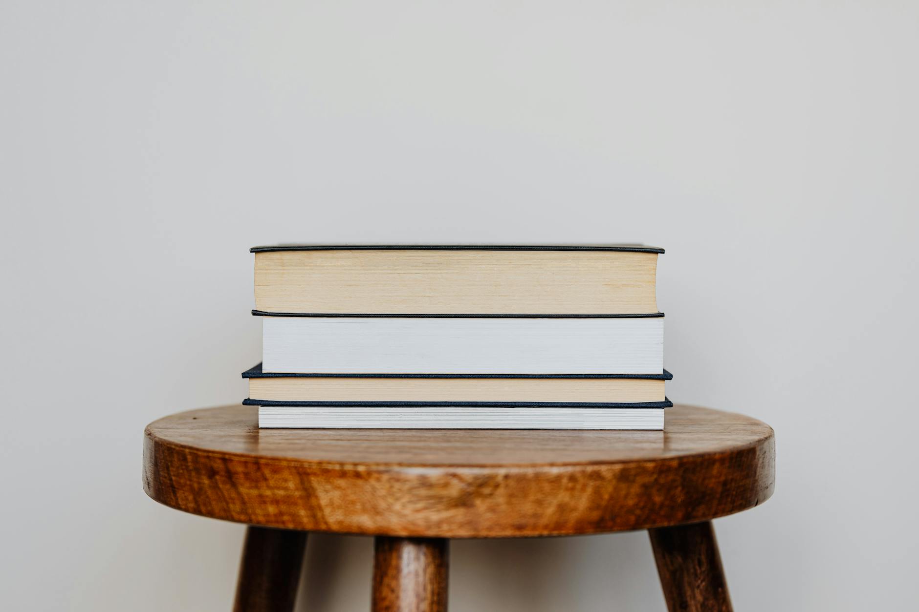 Stack of books arranged on a wooden table surface