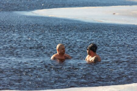 Person's legs submerged in ice-filled therapy tub for cold water treatment