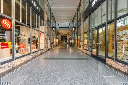 Modern shopping mall interior with storefronts and shoppers walking through corridors