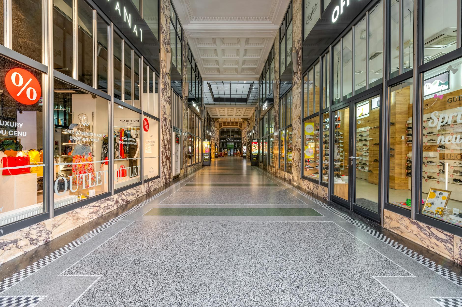Modern shopping mall interior with storefronts and shoppers walking through corridors