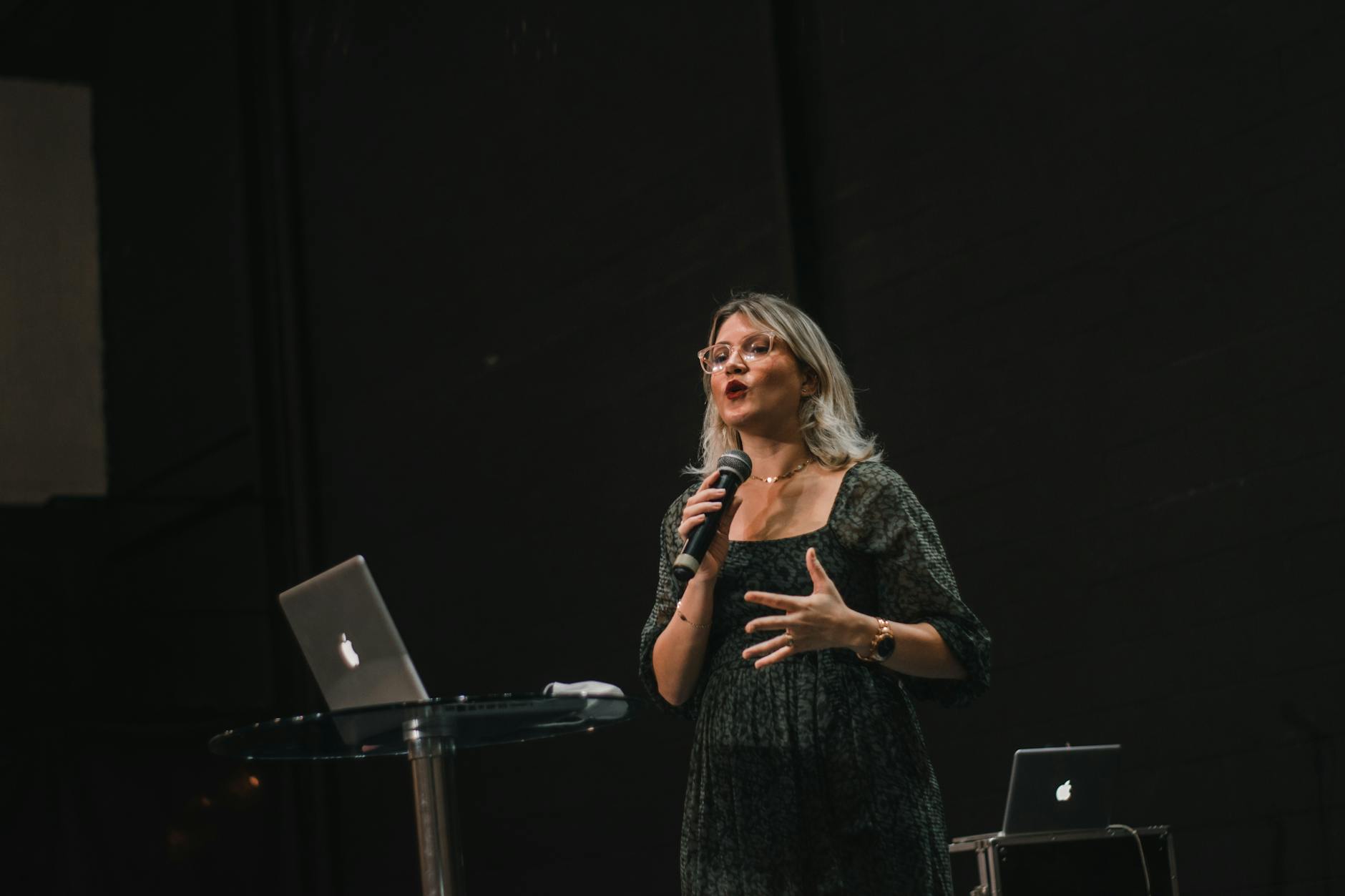 Female speaker addressing audience at podium with microphone during public speaking event
