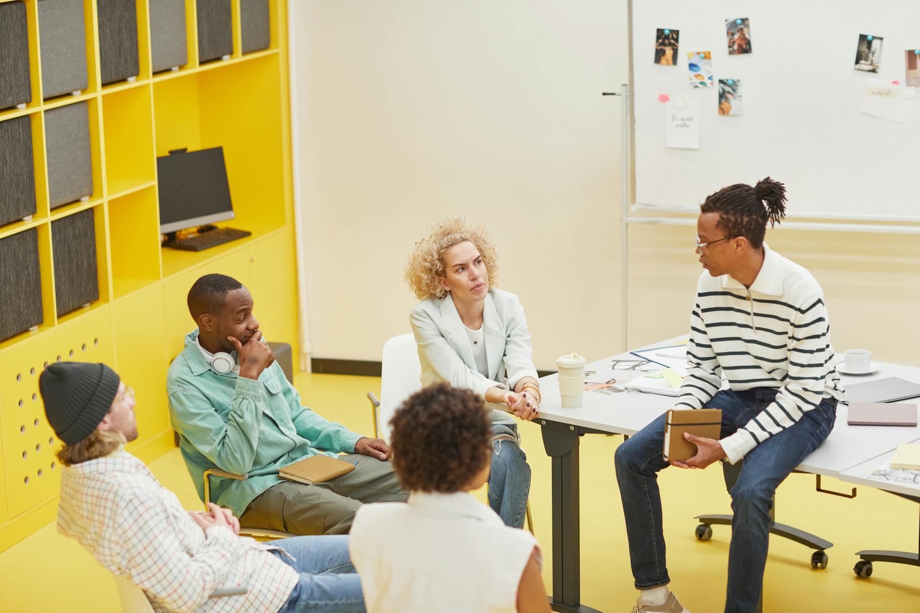 Group of creative professionals collaborating around a table with laptops and design materials
