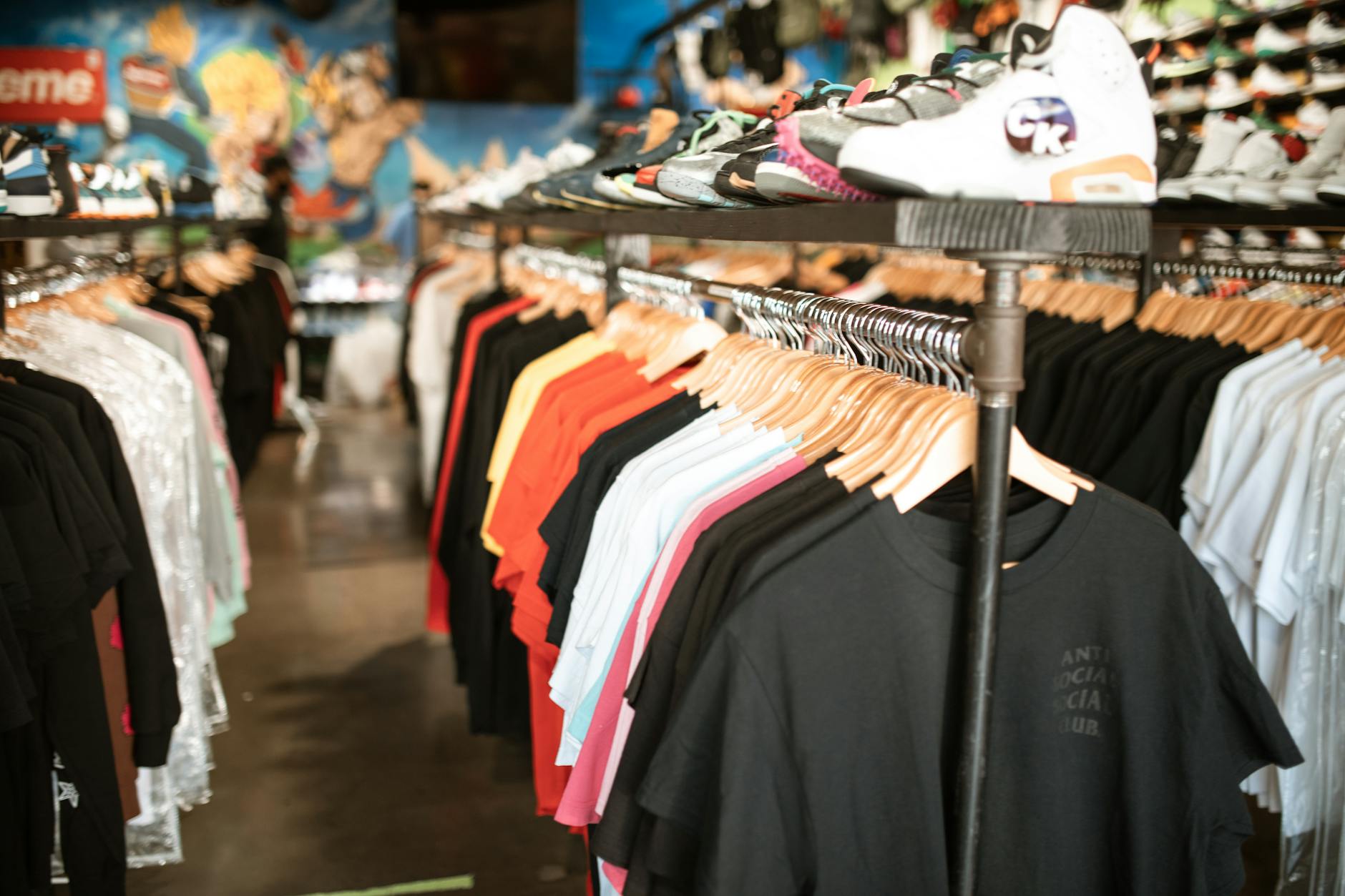 Clothing rack displaying various streetwear pieces including hoodies, jackets, and casual wear in urban retail setting