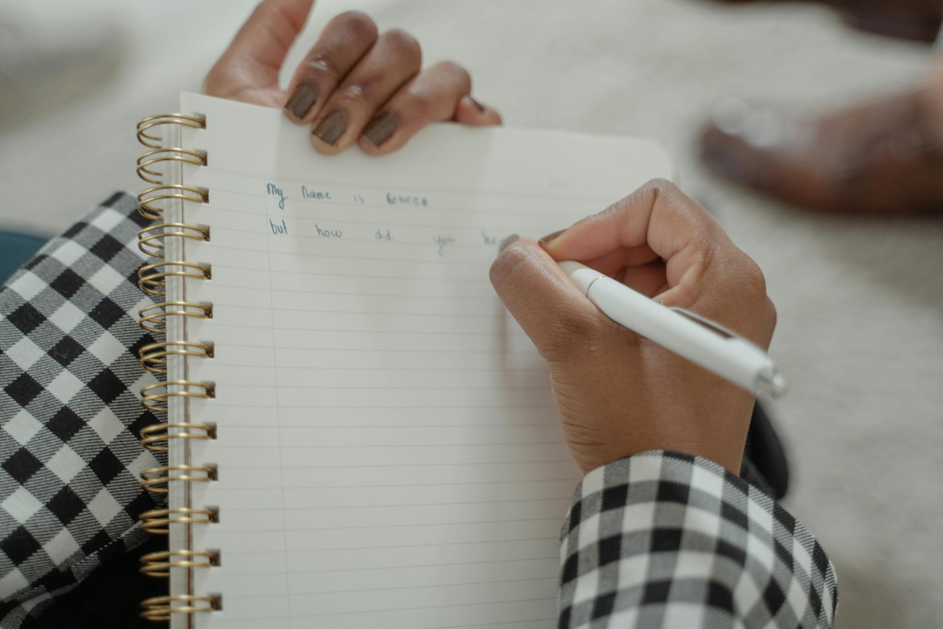 Person writing in notebook with pen on wooden desk during planning session