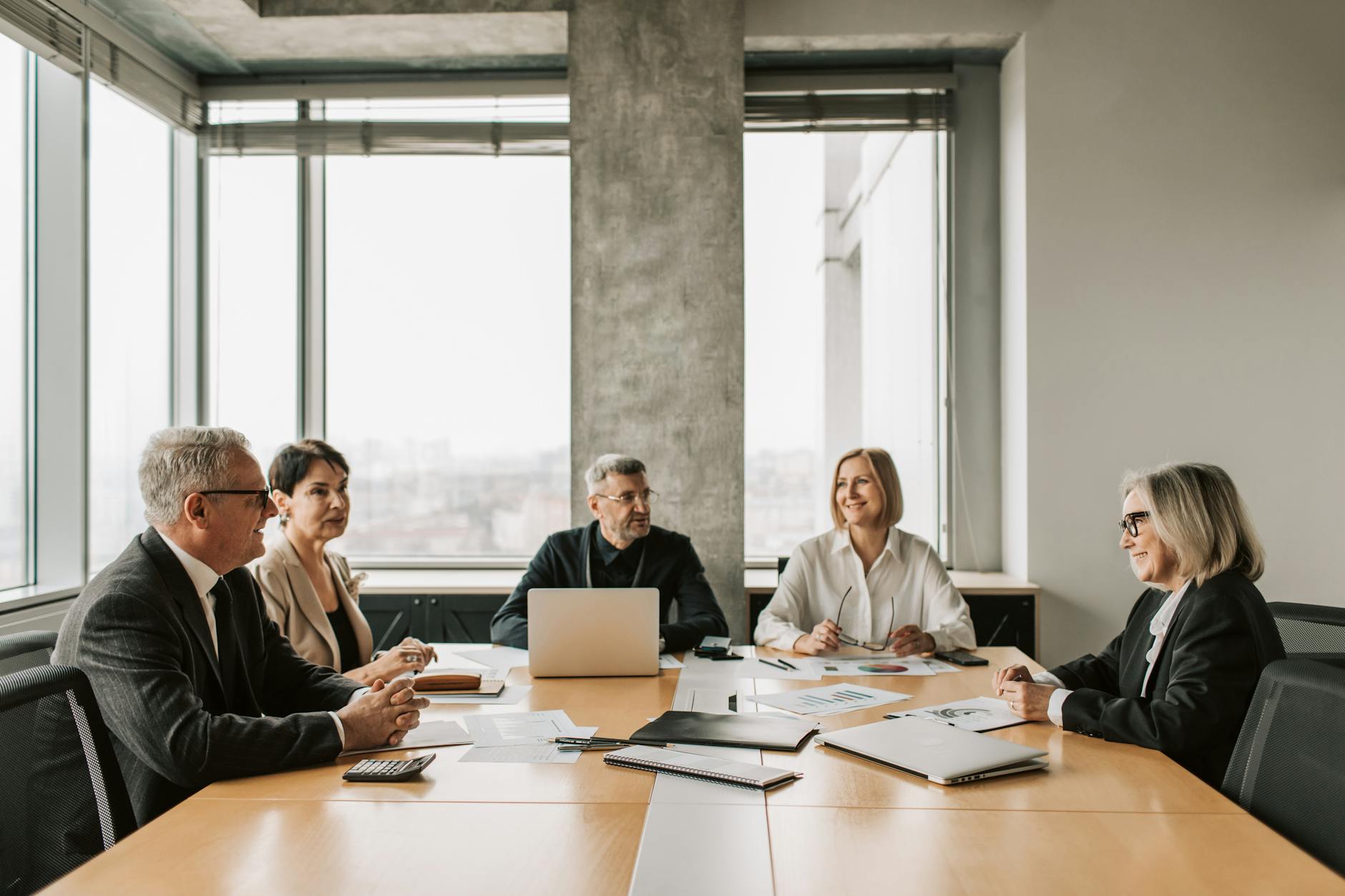 Business professionals meeting around conference table discussing partnership deals