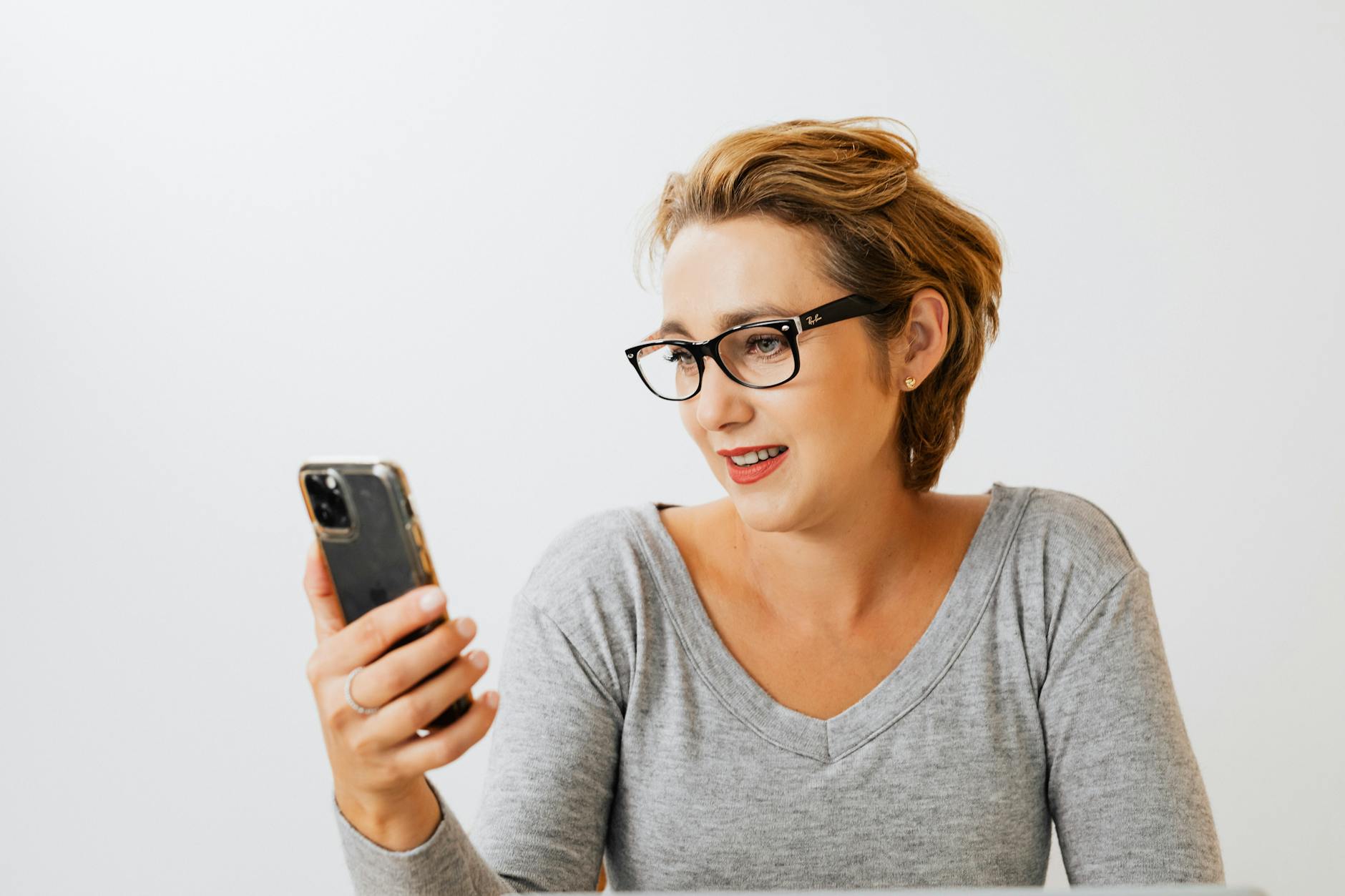 Woman looking at smartphone screen while holding a book