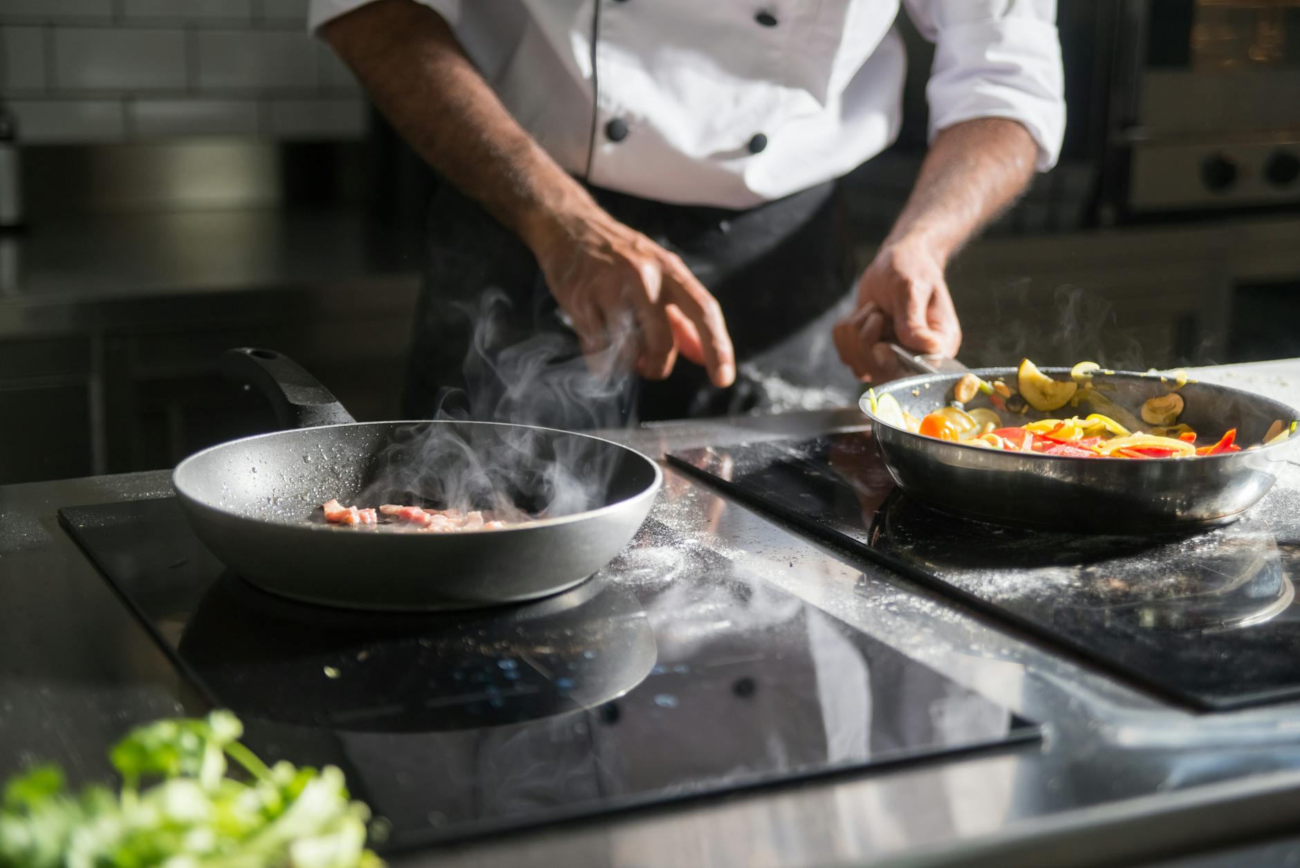 Professional chef preparing food in commercial kitchen with flames and cooking equipment