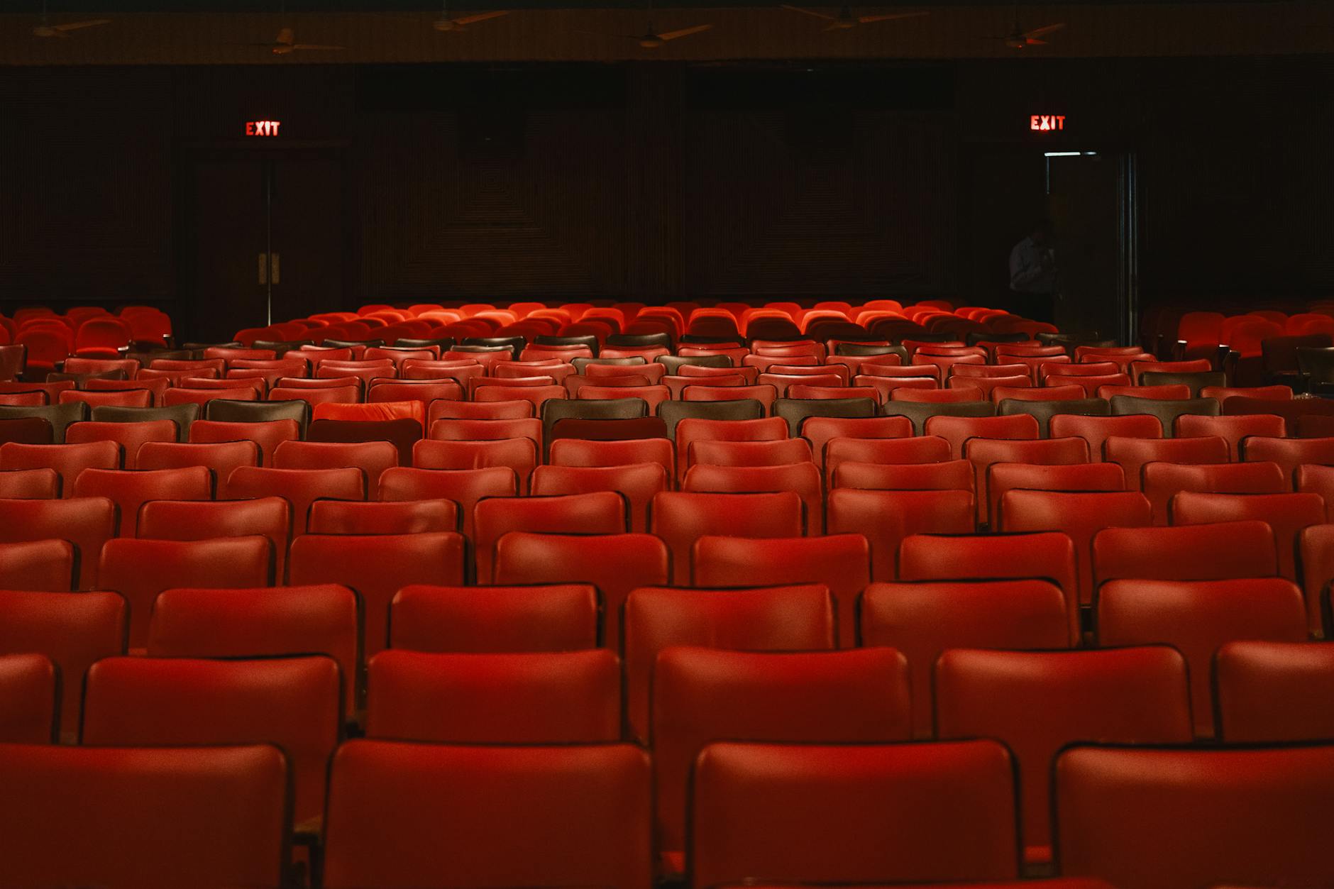 Empty movie theater seats facing large screen