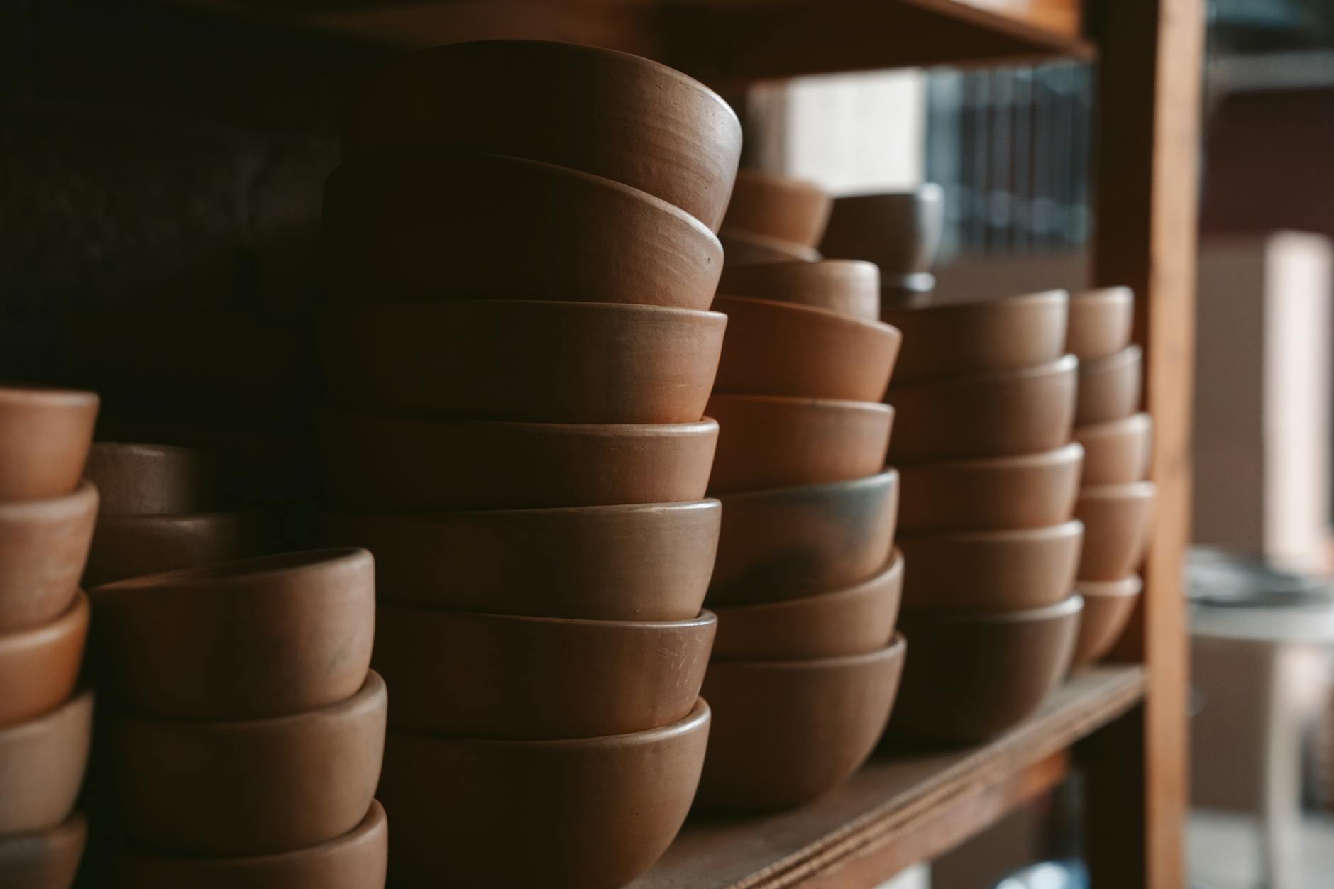 Collection of handmade ceramic bowls and pottery pieces on wooden table