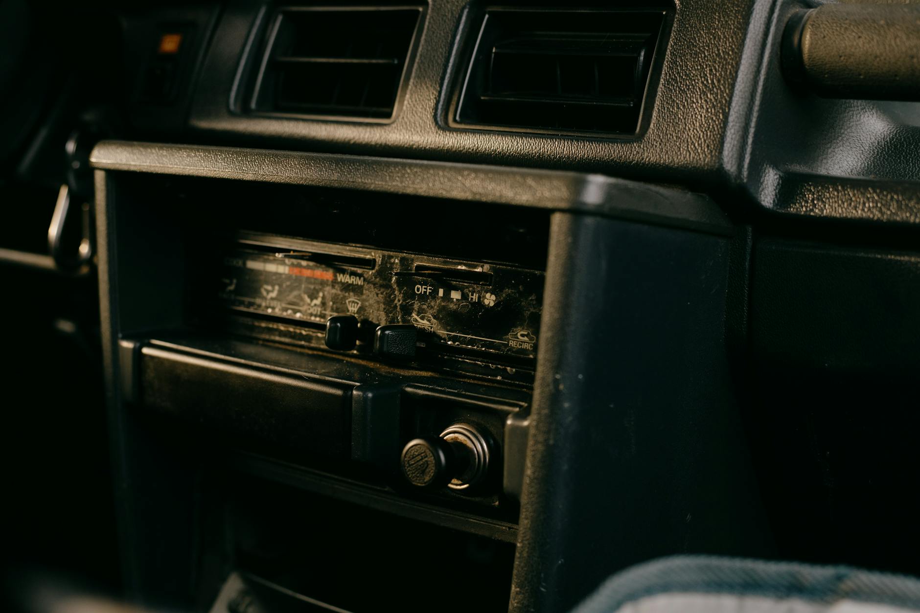 Person adjusting car radio dial while driving, dashboard visible