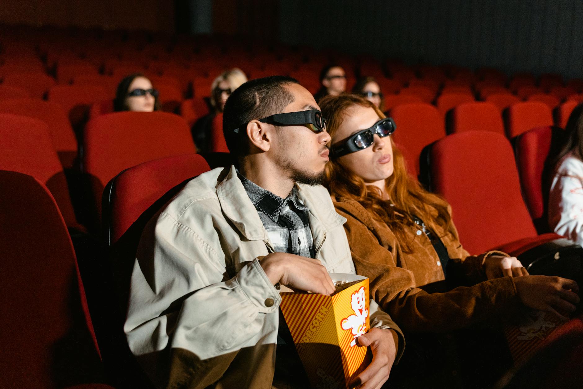 Movie theater audience watching film on large screen in darkened theater