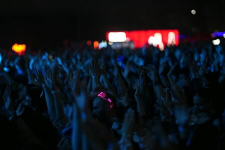 Large crowd at a nighttime music concert with stage lights overhead