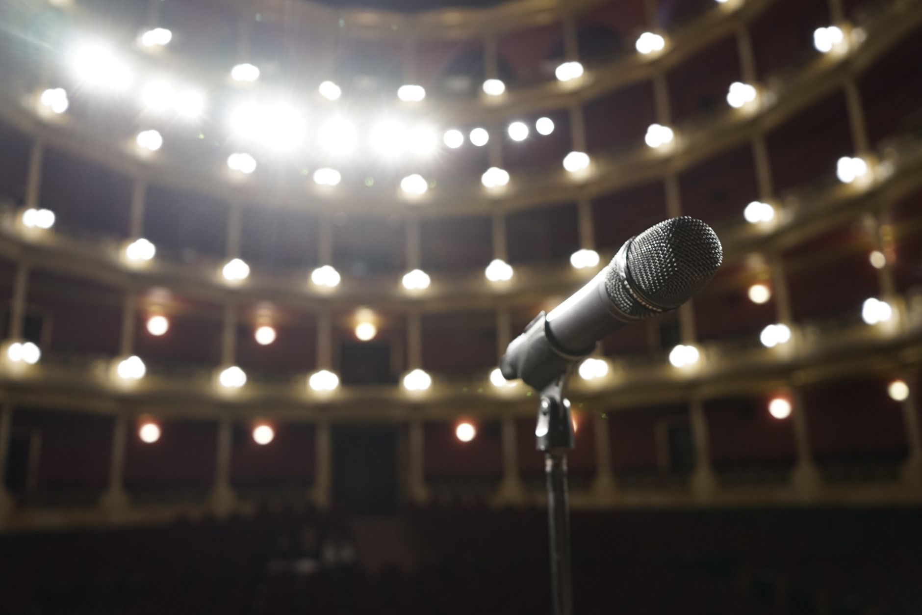 Empty theater stage lit by a single spotlight, representing performance and dramatic artistry