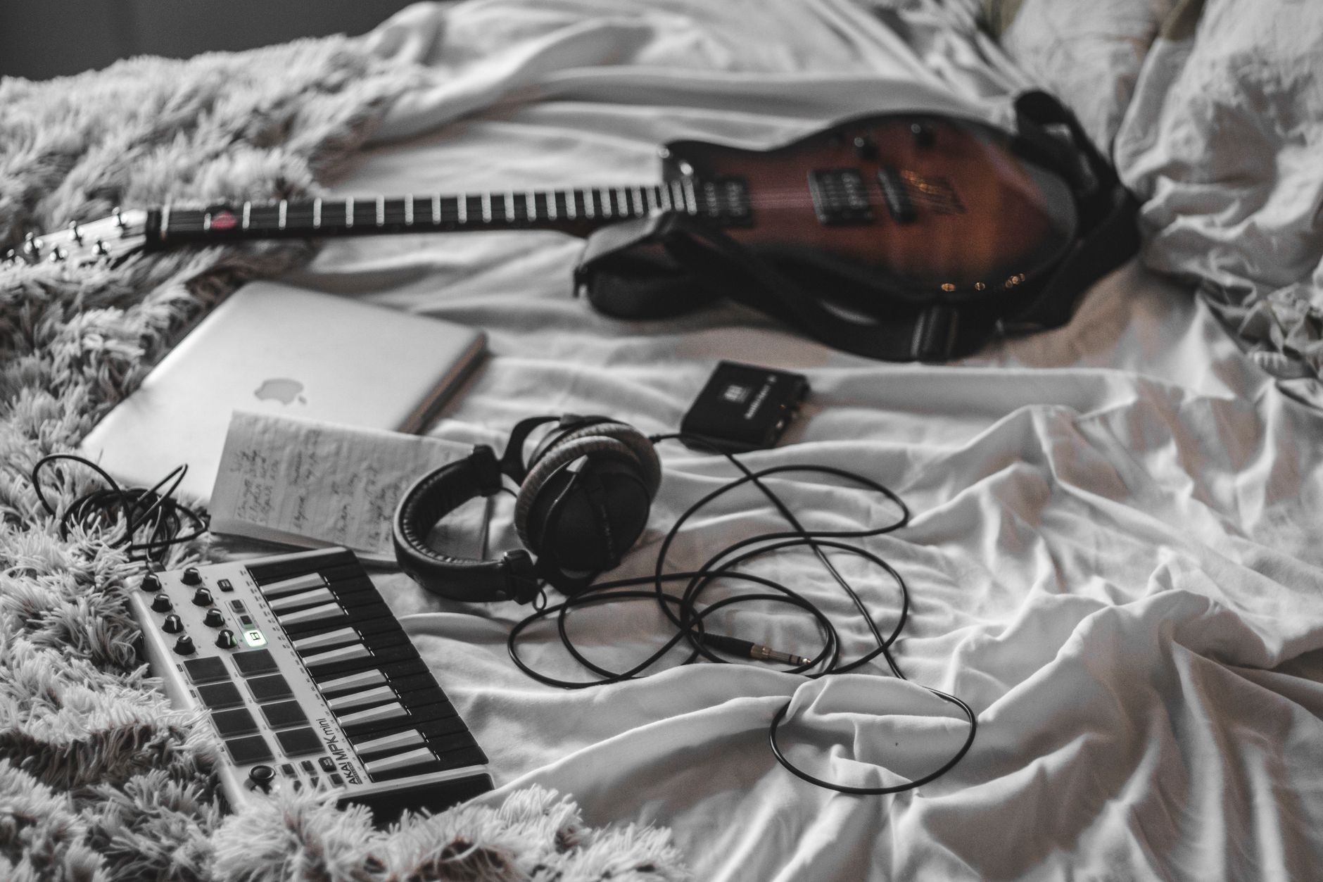 A young artist recording music in a home bedroom studio setup with a laptop and microphone
