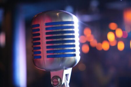 Comedy Central’s Late-Night Strategy Shift Toward Younger Stand-Up Talent Professional microphone on dimly lit comedy club stage with spotlights