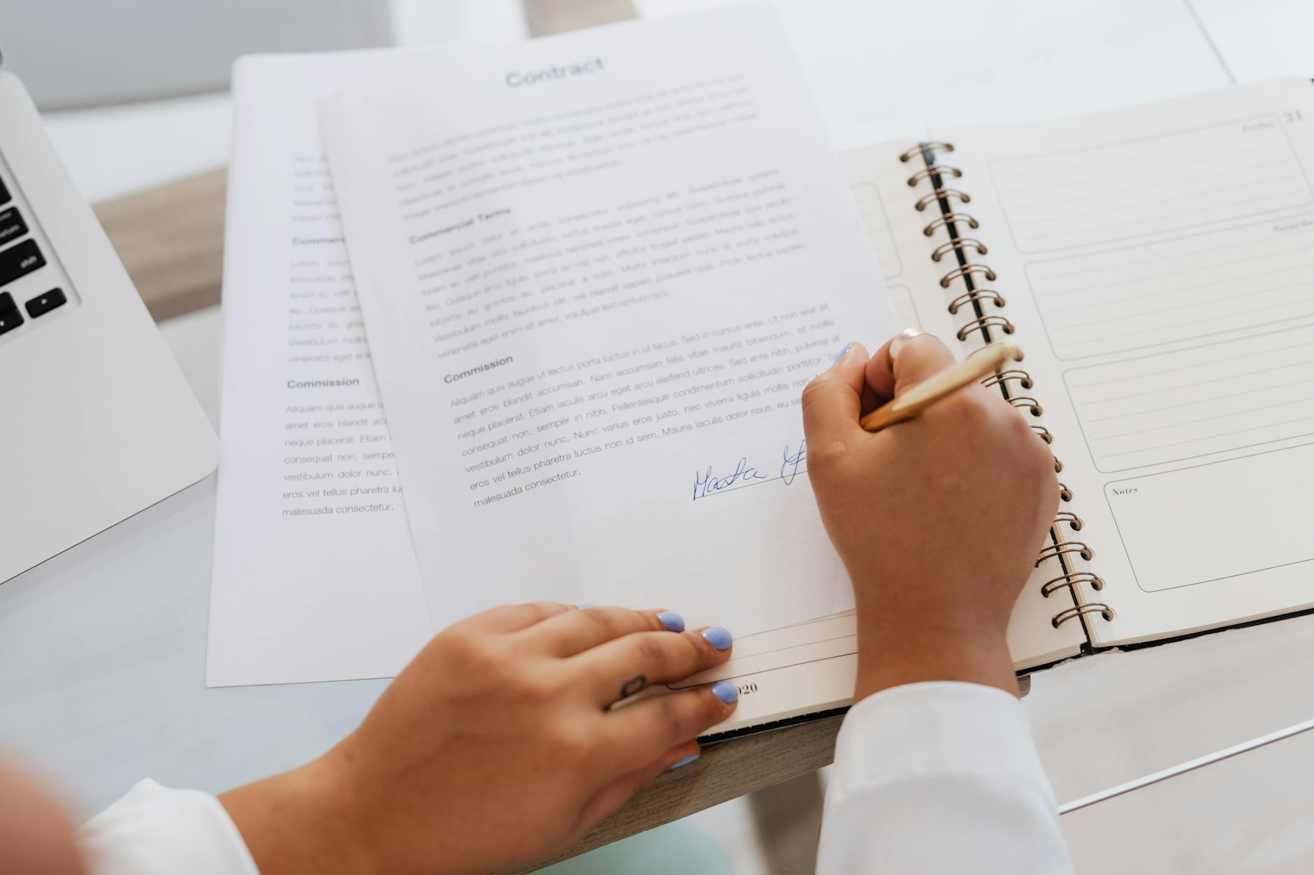 Person signing a document at a desk representing a music industry contract