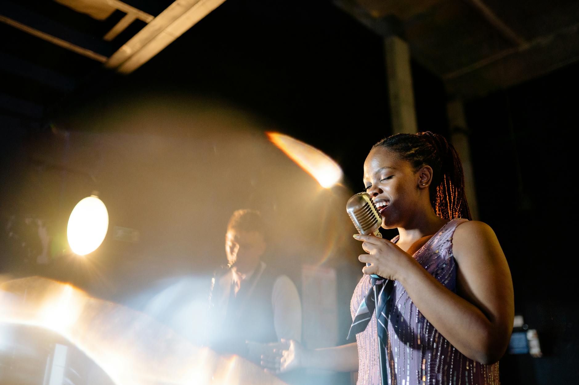 Young performer standing in dramatic stage lighting during live performance