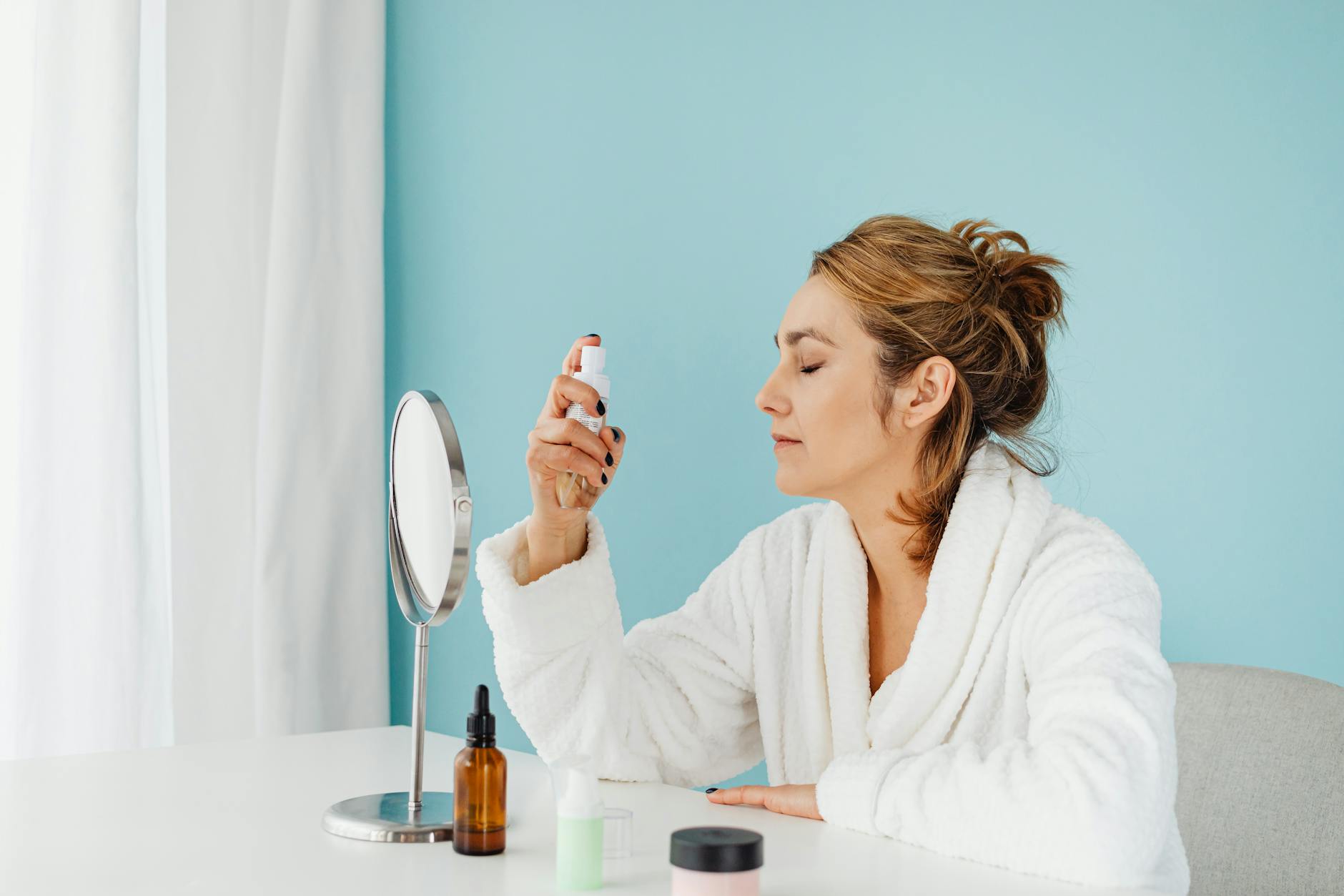 Woman applying skincare product to face in natural lighting