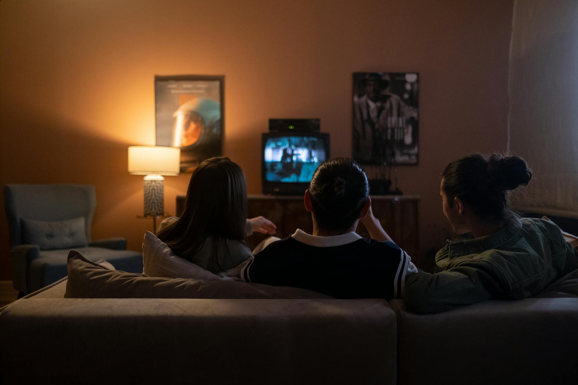 Group of people sitting on couch watching television together in living room