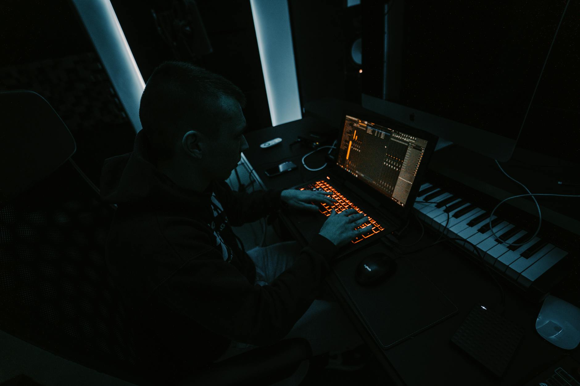 A musician recording audio on a laptop in a casual home environment