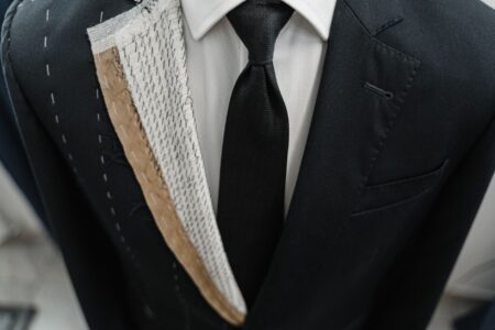 A sharply structured women's tailored jacket displayed against a neutral background, emphasizing silhouette and construction