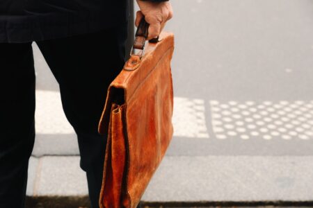 A structured vintage leather handbag with a curved bamboo handle on a neutral background