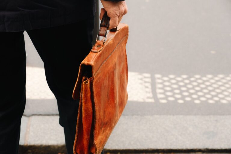 A structured vintage leather handbag with a curved bamboo handle on a neutral background