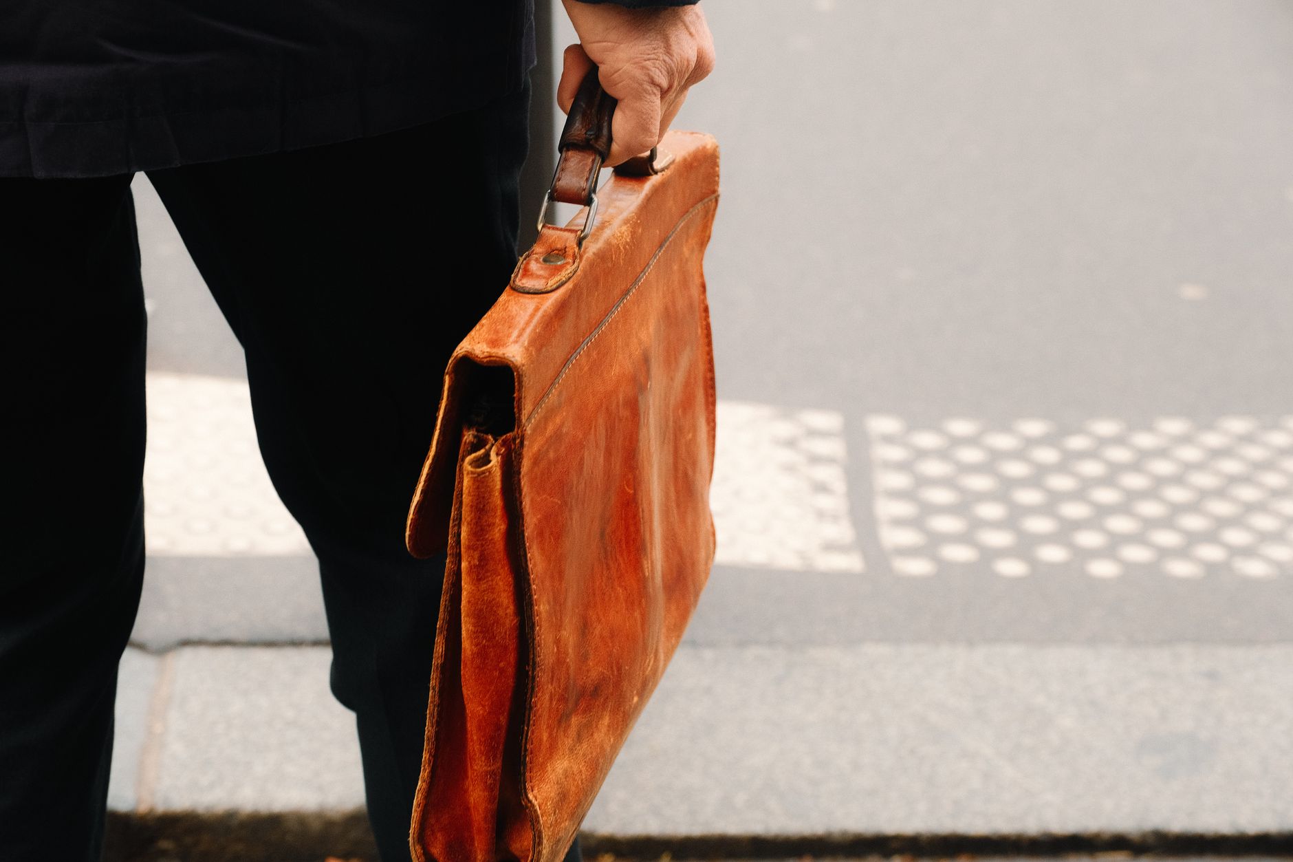A structured vintage leather handbag with a curved bamboo handle on a neutral background