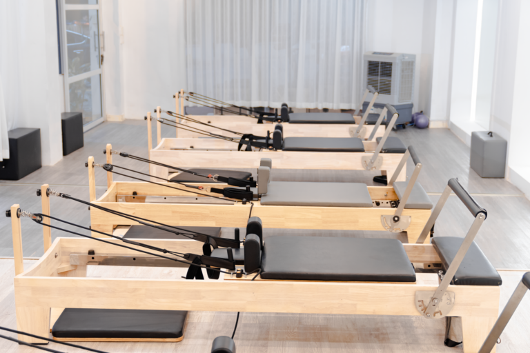 Reformer Pilates Studios Are Edging Out Traditional Gyms in Major Cities A bright reformer Pilates studio with rows of reformer machines ready for class