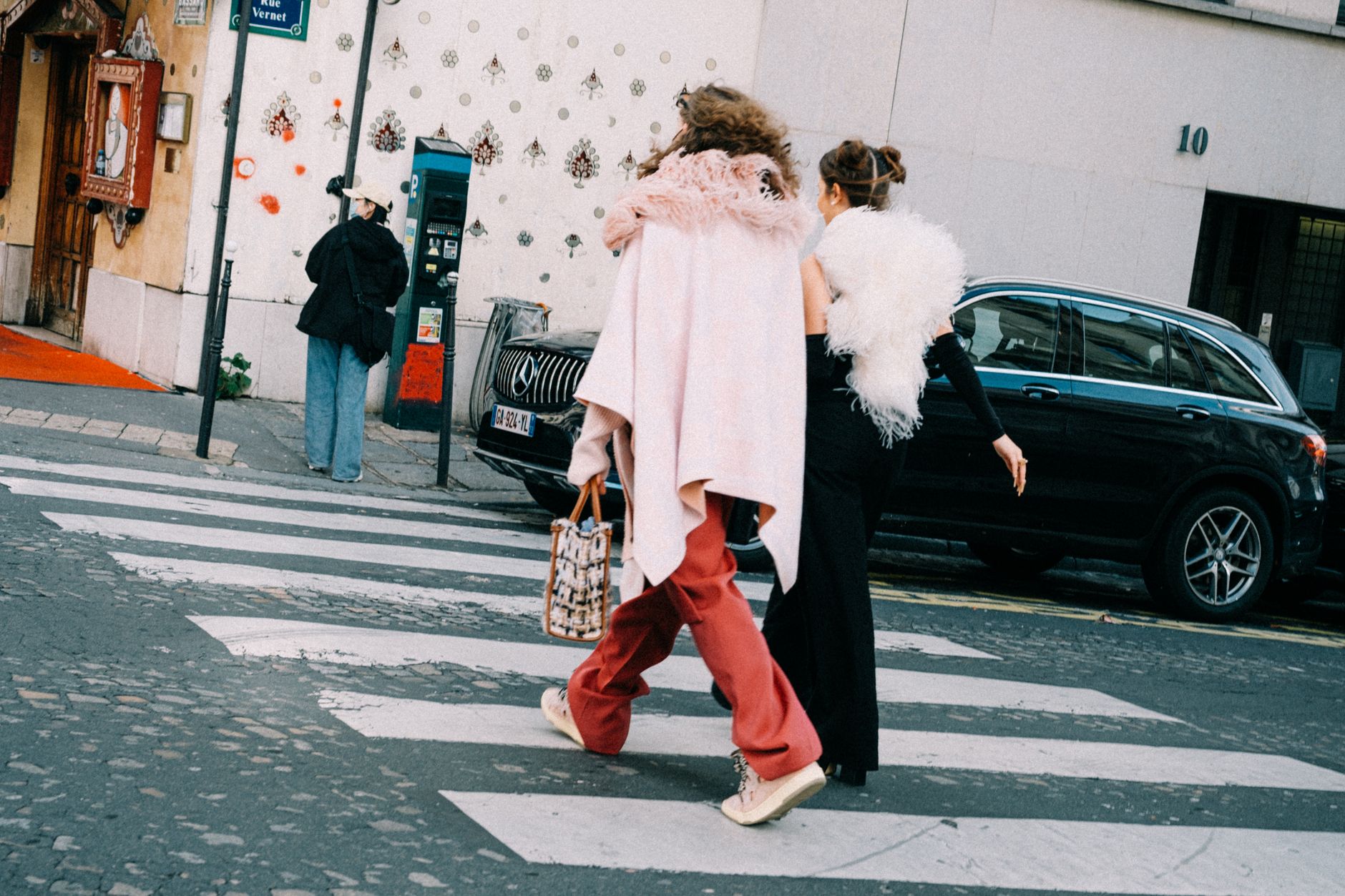 A person dressed in minimalist street style clothing walking on a city pavement