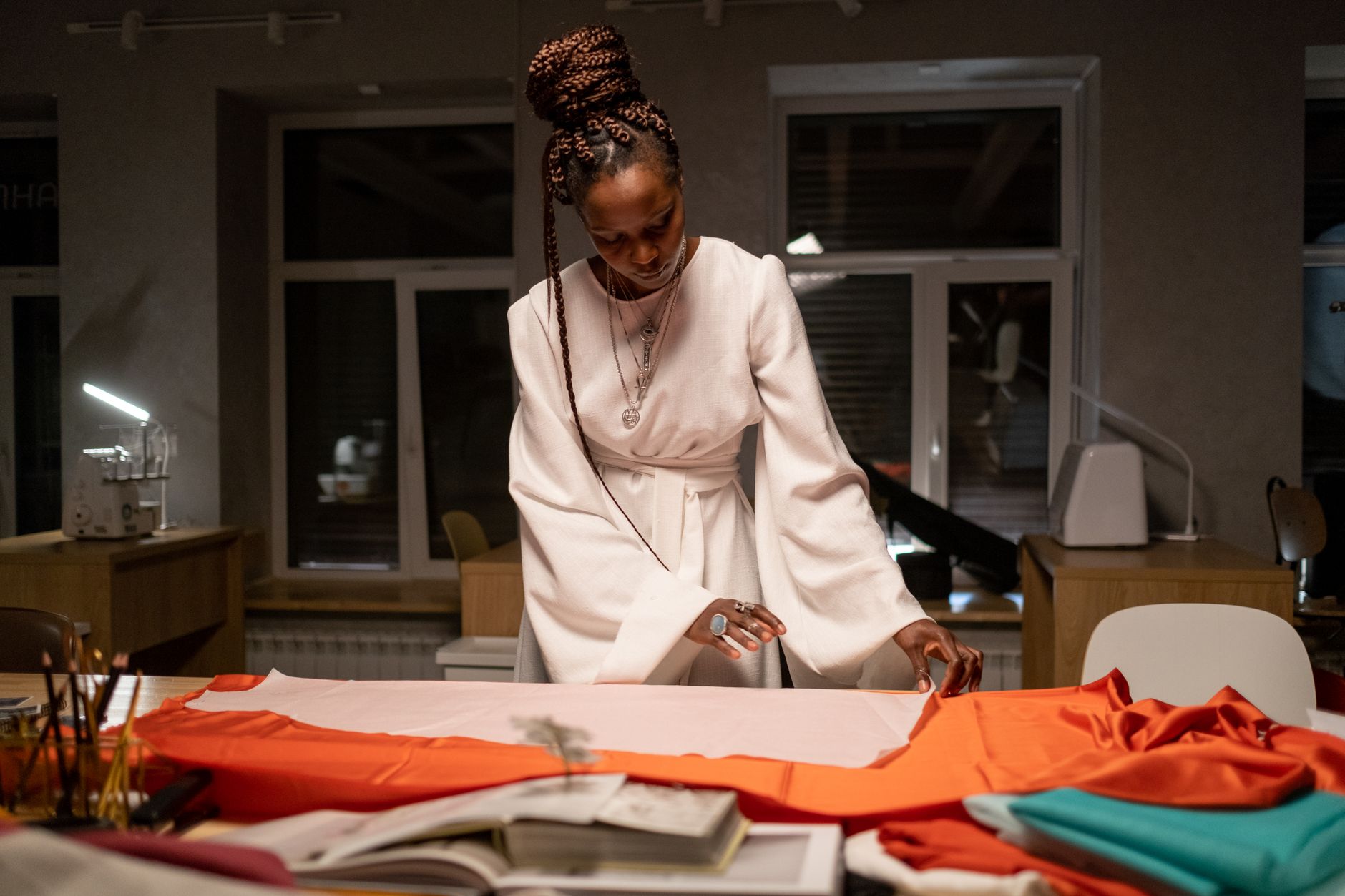 A designer reviewing garment sketches and fabric swatches in a studio workspace