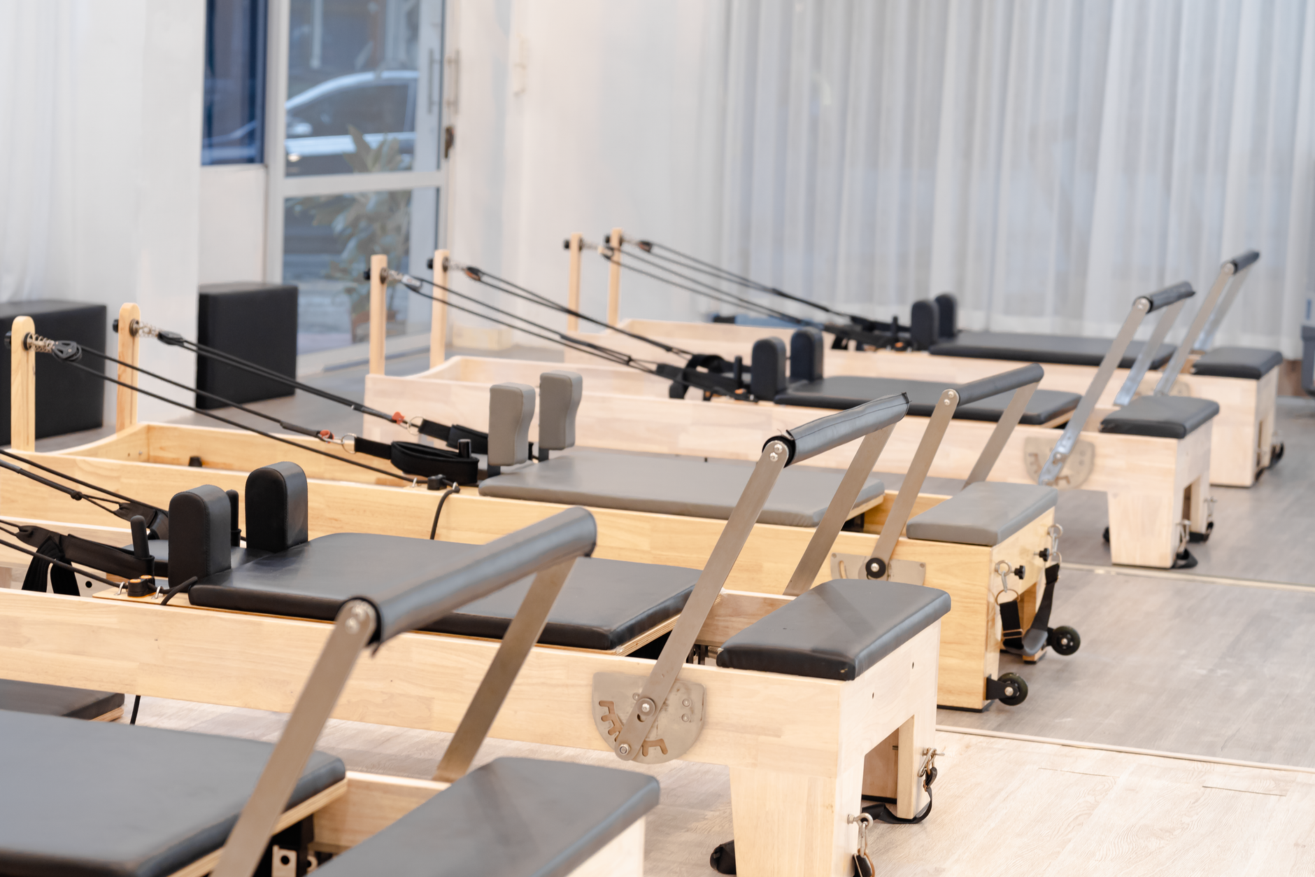 A person using a reformer machine during a Pilates session with an instructor nearby