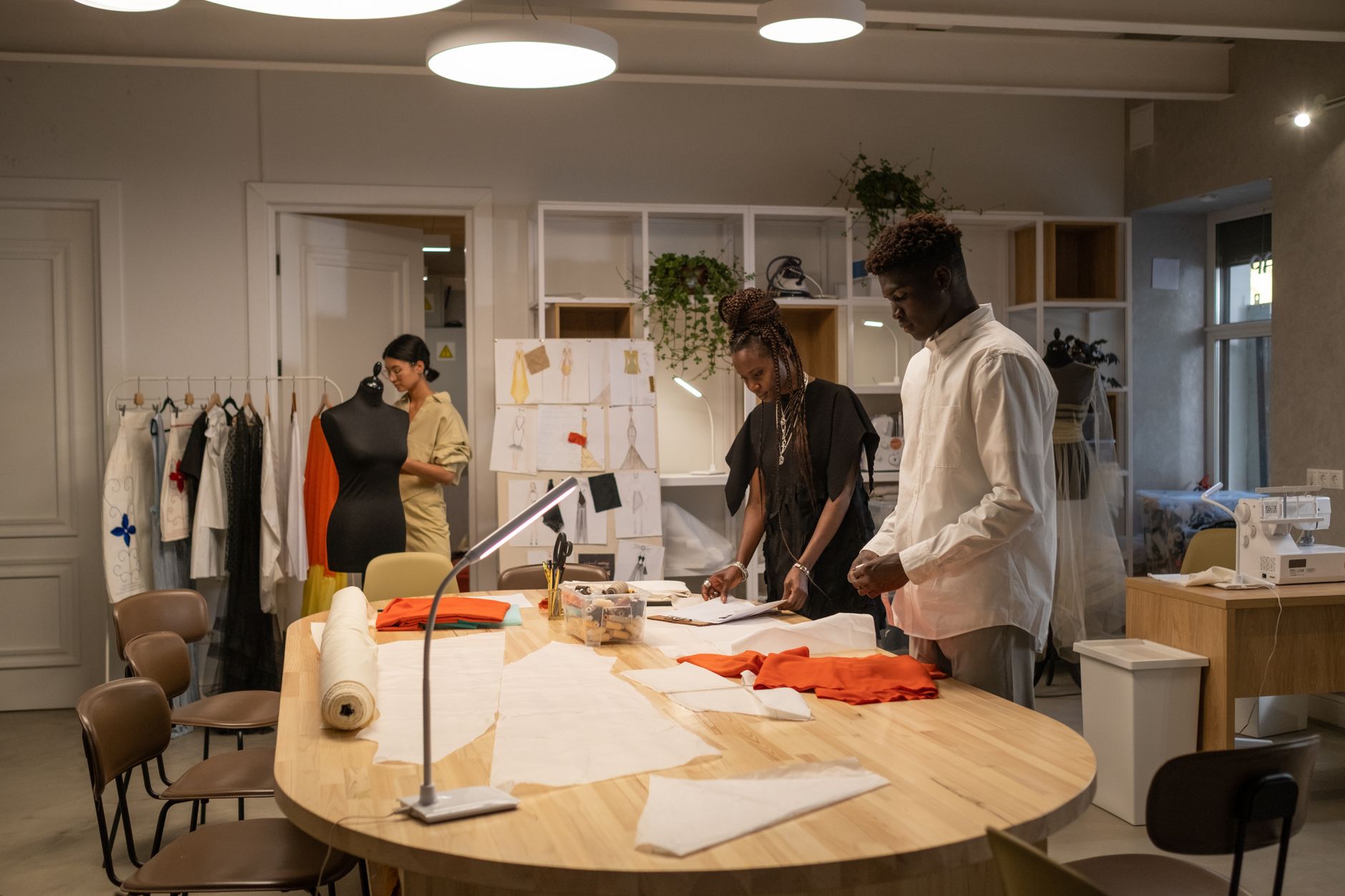 Fashion designer working in a modern atelier surrounded by garment samples