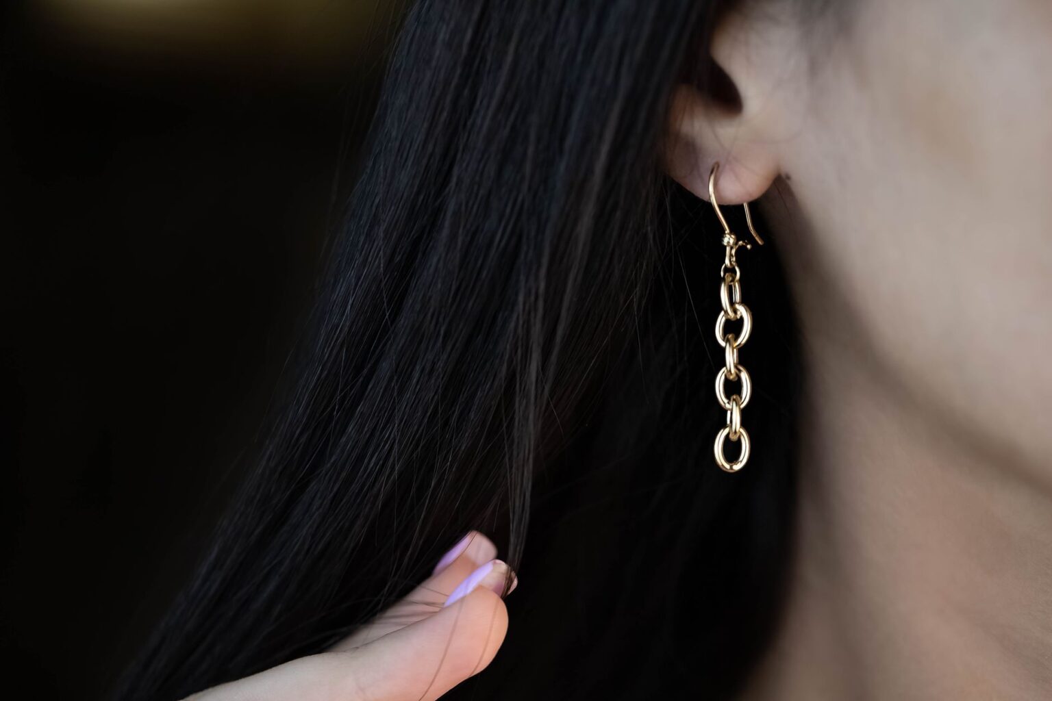 Bottega Veneta’s Drop Earring Is Quietly Edging Out the Cuff Close-up of elongated gold drop earrings against a neutral background