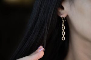 Bottega Veneta’s Drop Earring Is Quietly Edging Out the Cuff Close-up of elongated gold drop earrings against a neutral background