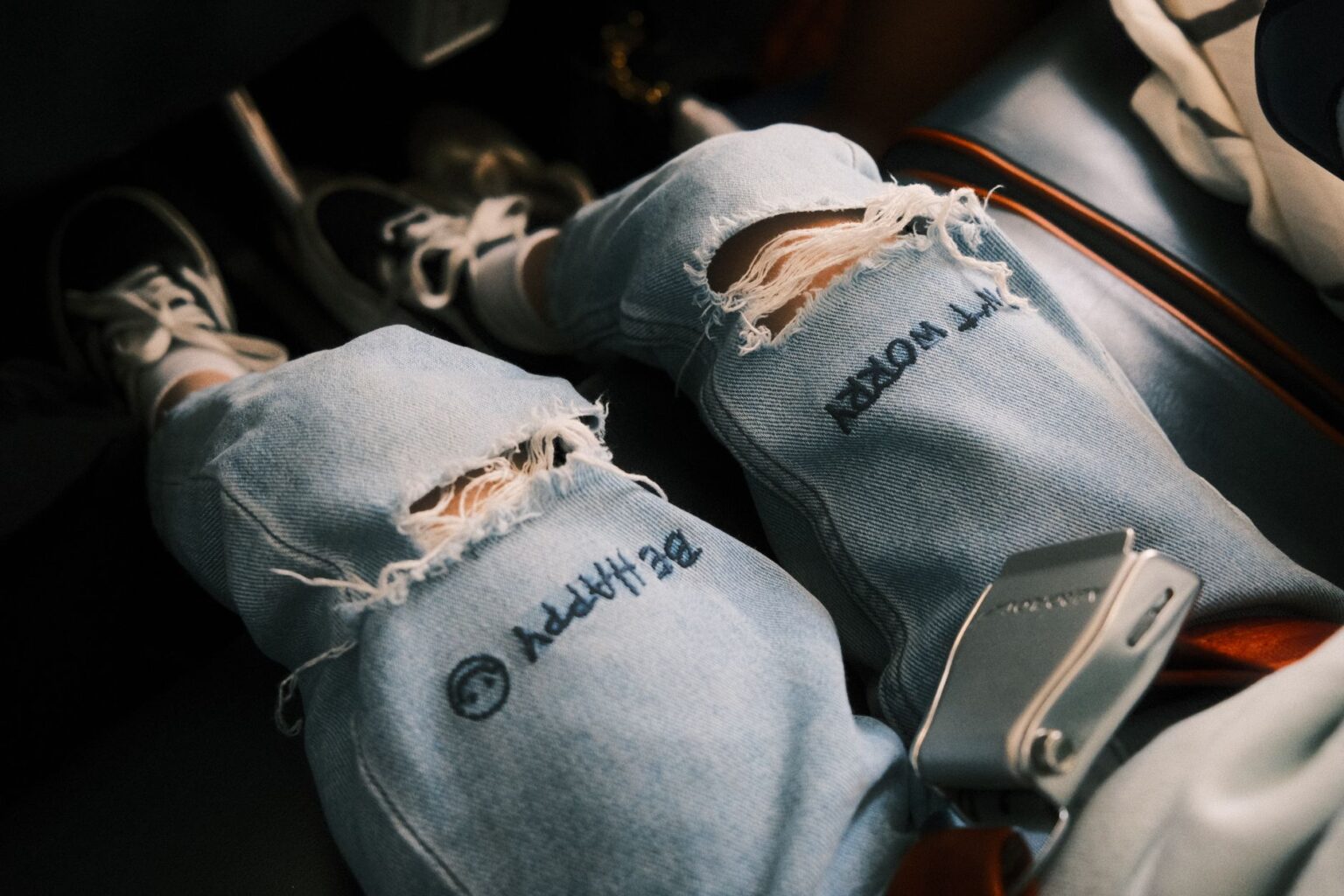 Acne Studios’ Distressed Denim Is Quietly Edging Out the Tailored Jean Close-up of worn distressed denim jeans with faded wash and frayed details