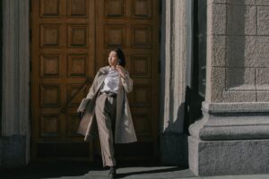 Toteme’s Belted Trench Is Quietly Edging Out the Wrap Coat Woman wearing a structured belted trench coat on a city street