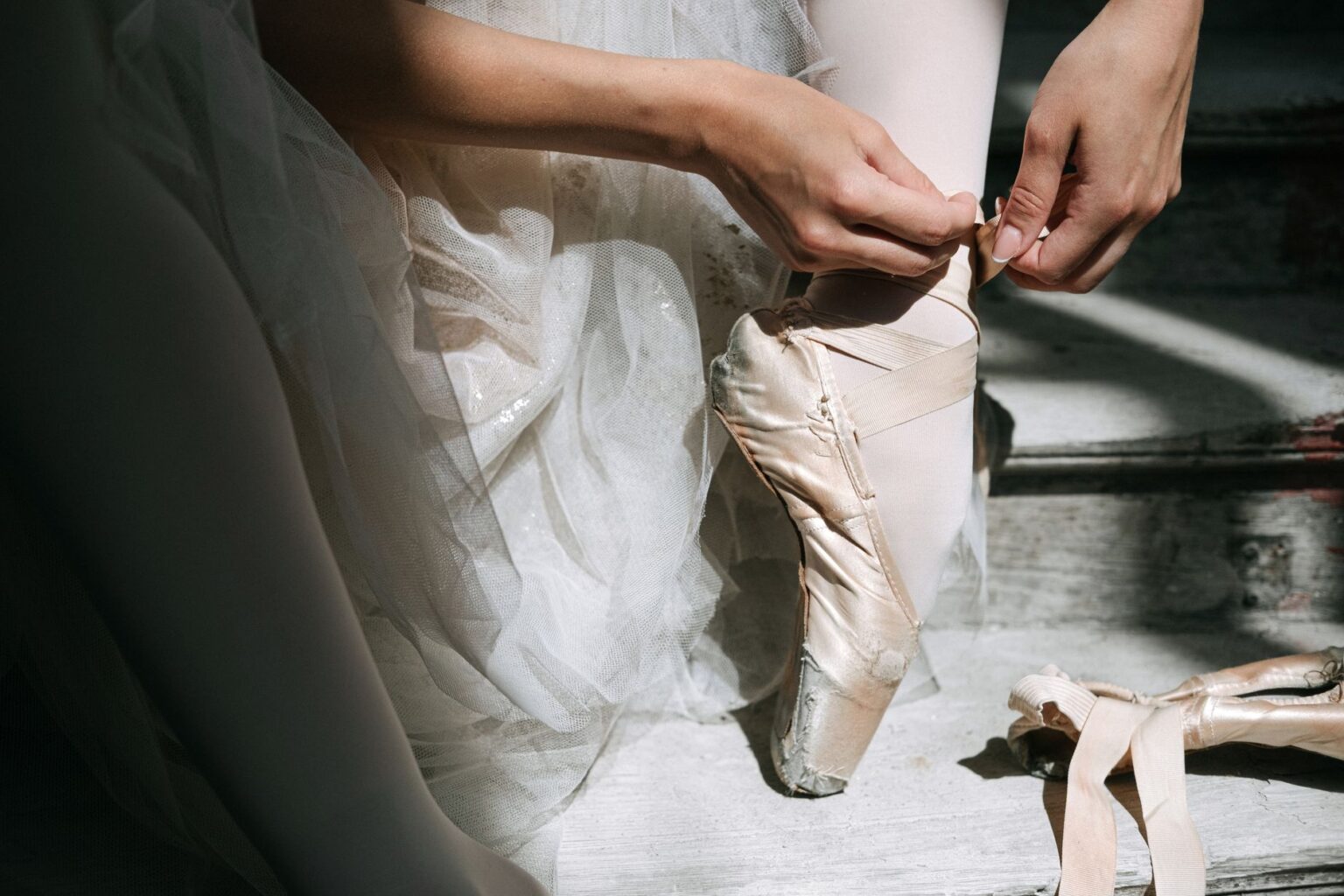 Freed’s Satin Pointe Shoe Is Quietly Edging Out the Loafer Close-up of satin ballet pointe shoes with ribbon ties on a wooden floor