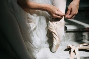 Freed’s Satin Pointe Shoe Is Quietly Edging Out the Loafer Close-up of satin ballet pointe shoes with ribbon ties on a wooden floor