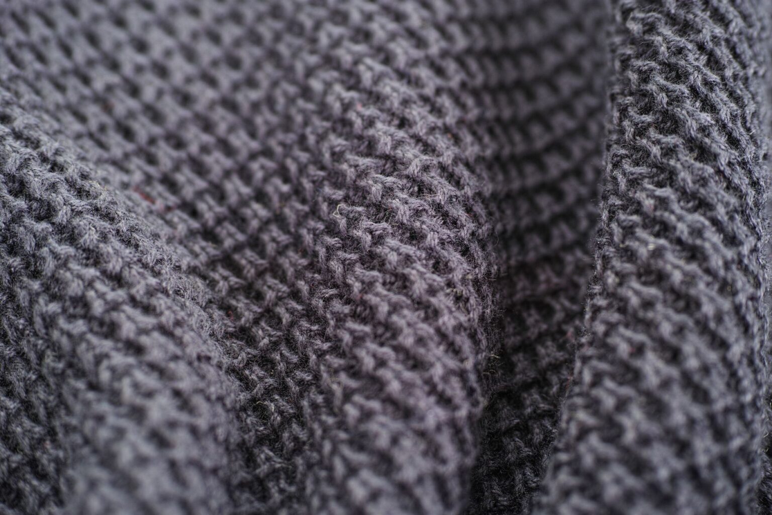 A finely knit merino wool sweater in a neutral cream tone folded neatly on a surface