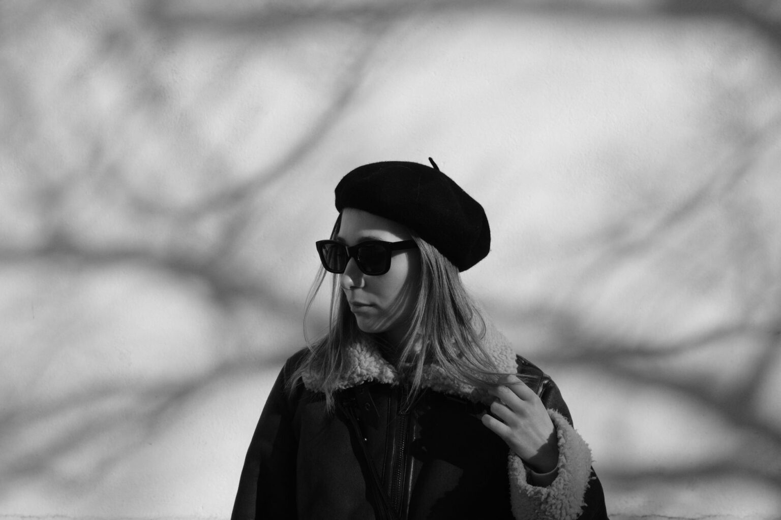 A woman wearing a fitted cashmere beret with a tailored coat in an urban setting
