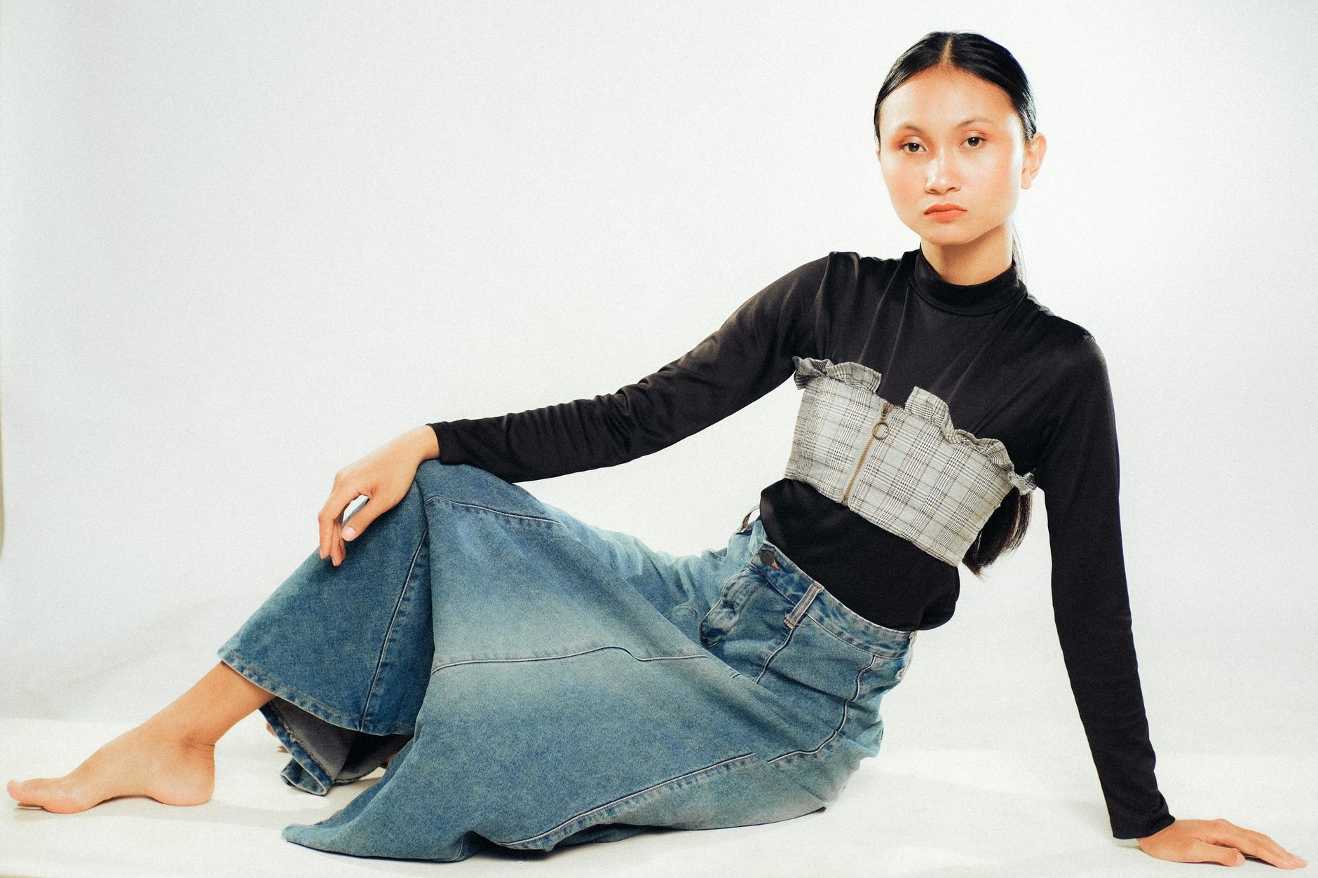 Model wearing loose denim jeans styled with structured outerwear in a fashion editorial setting