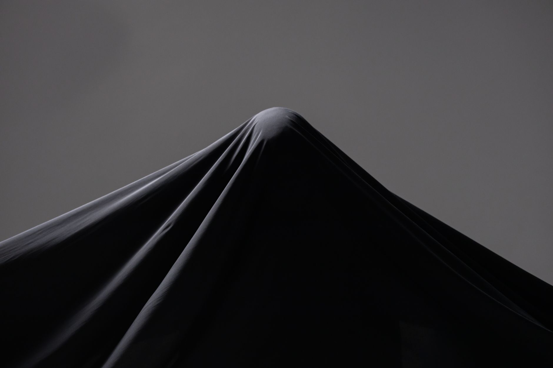 Close-up of black draped fabric with architectural folds and sculptural texture