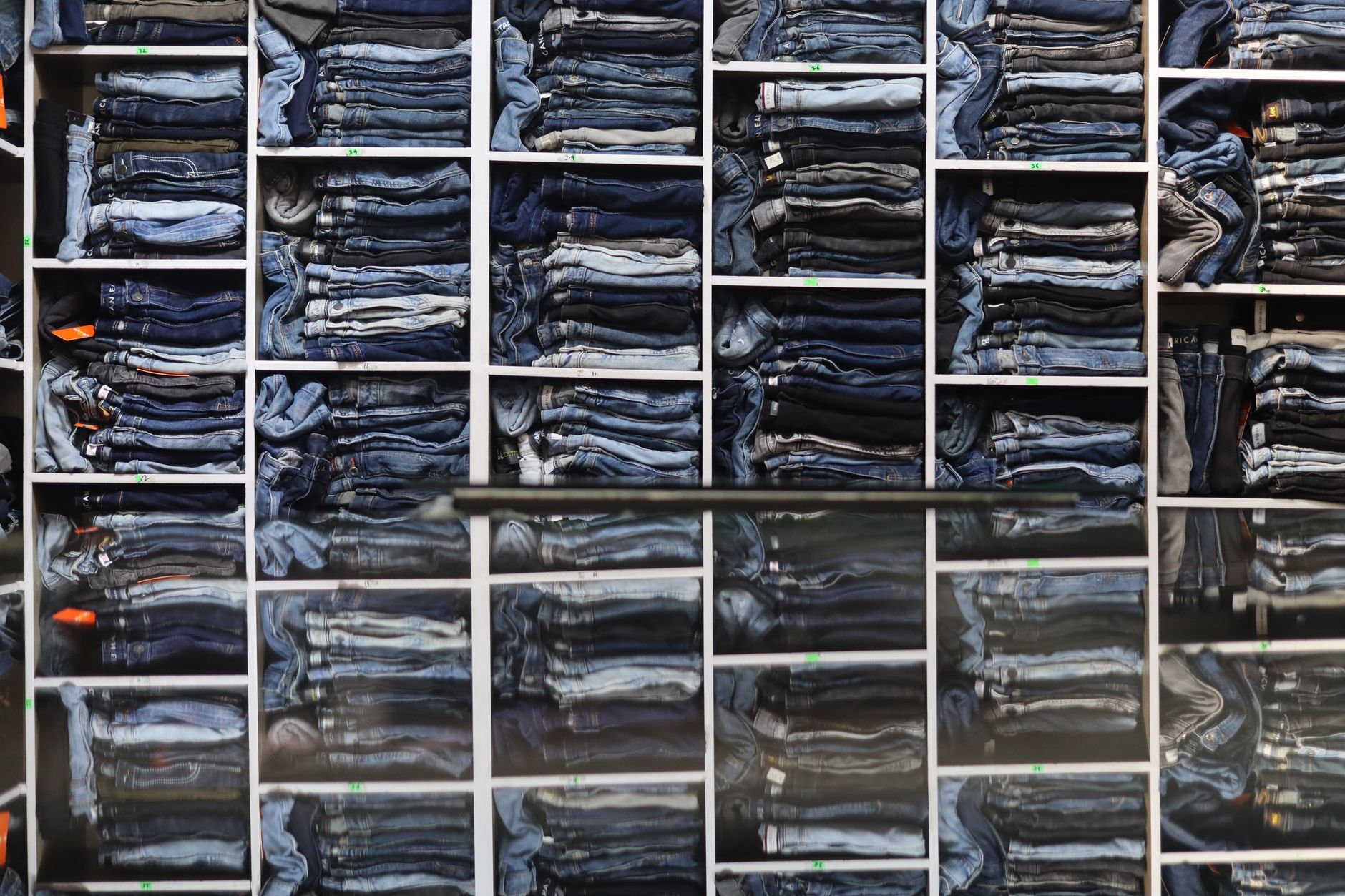 Row of denim jeans hanging on a clothing rack in a minimalist retail space