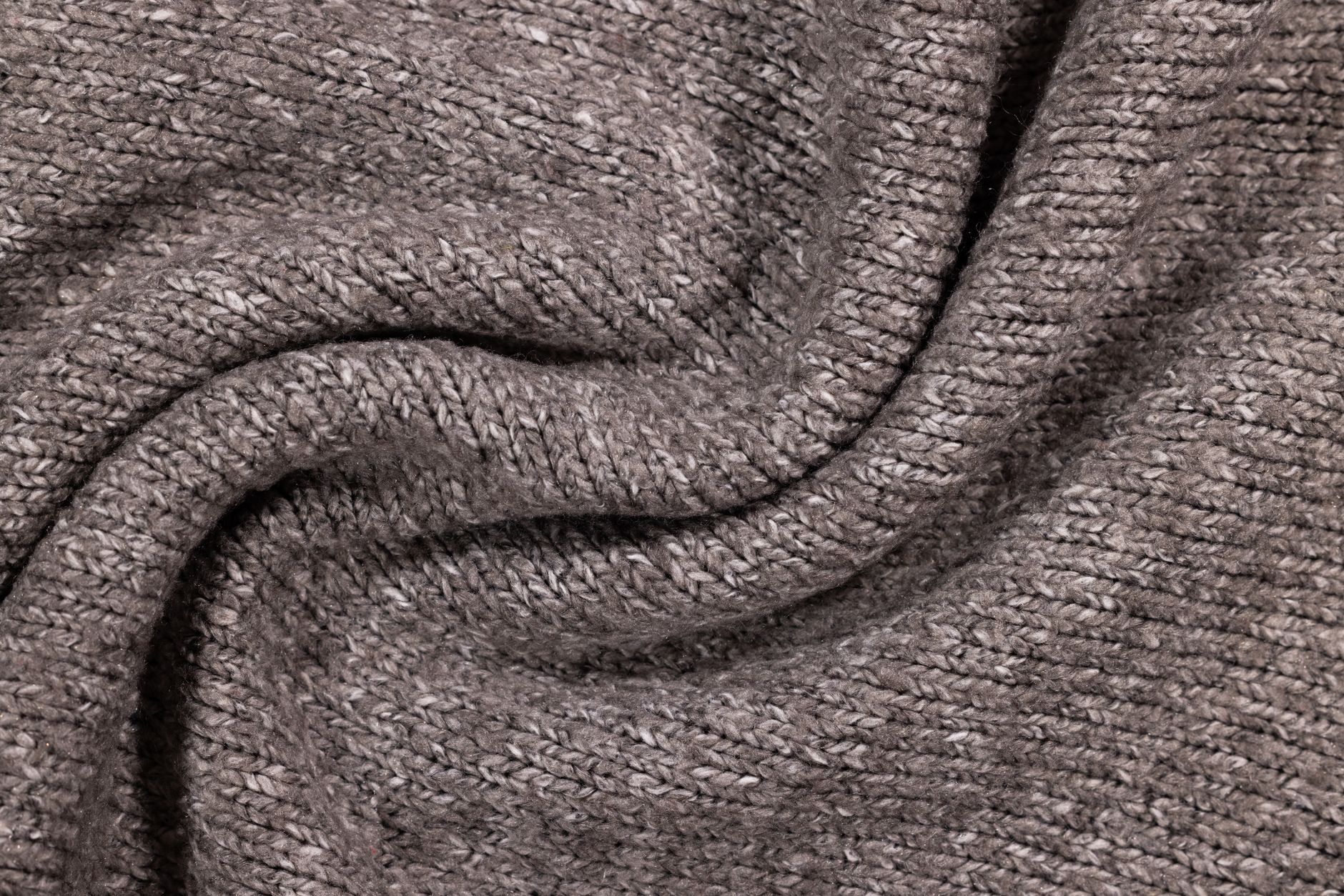 Neatly folded luxury knit sweaters in neutral tones stacked on a surface