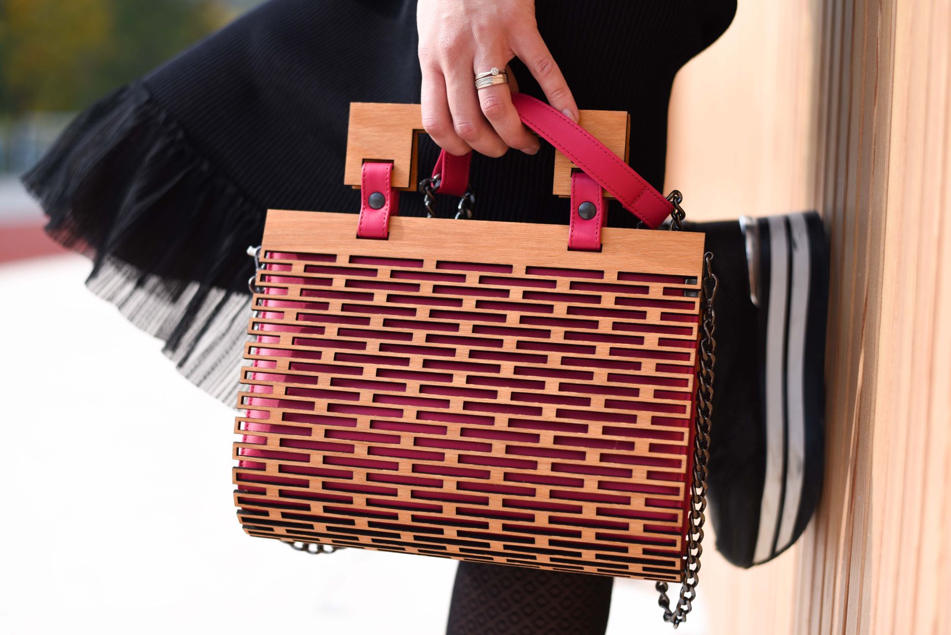A close-up of a woven leather luxury handbag with knotted handle detail