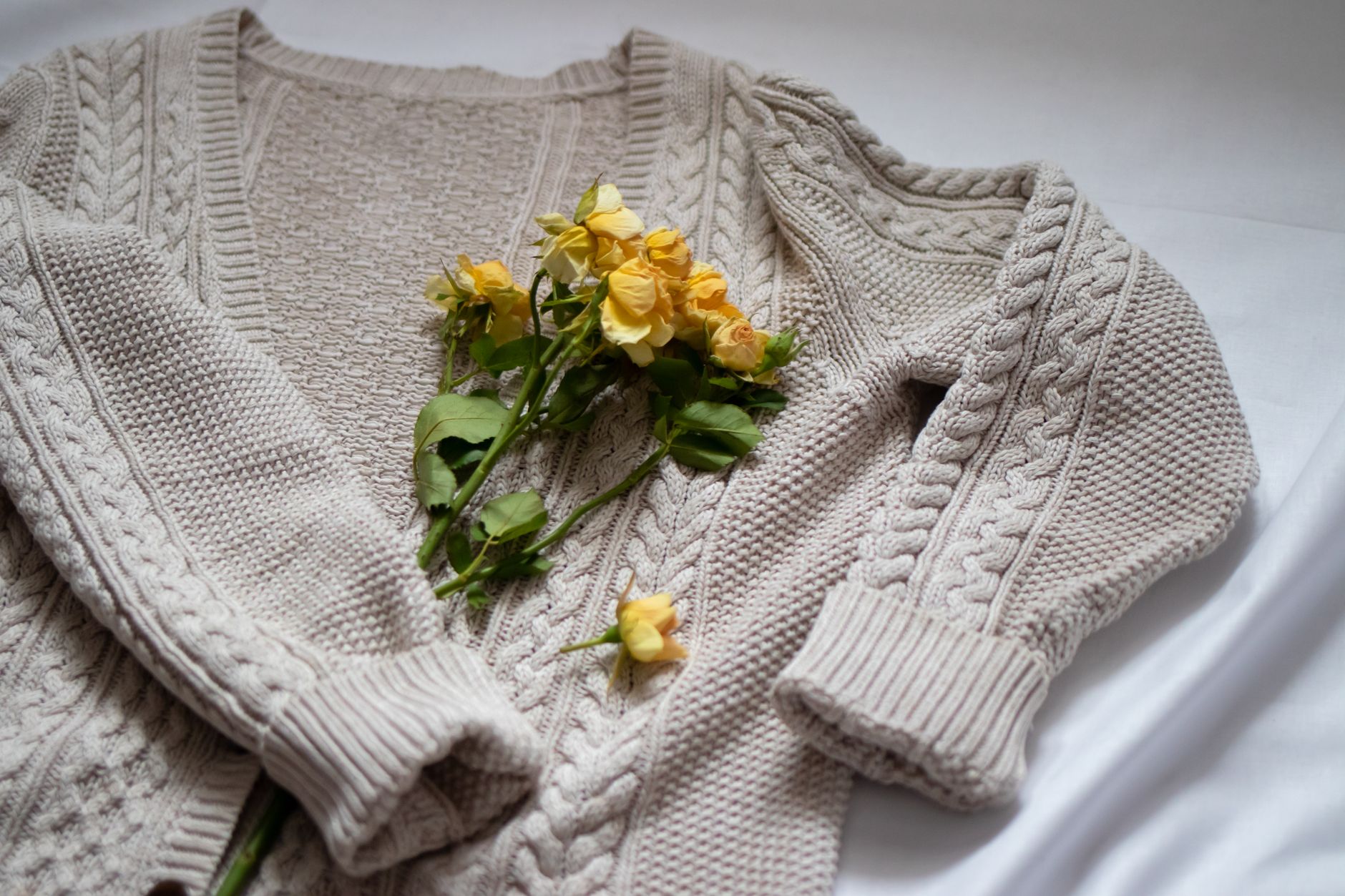 A neatly folded soft cashmere cardigan in a neutral tone displayed on a flat surface