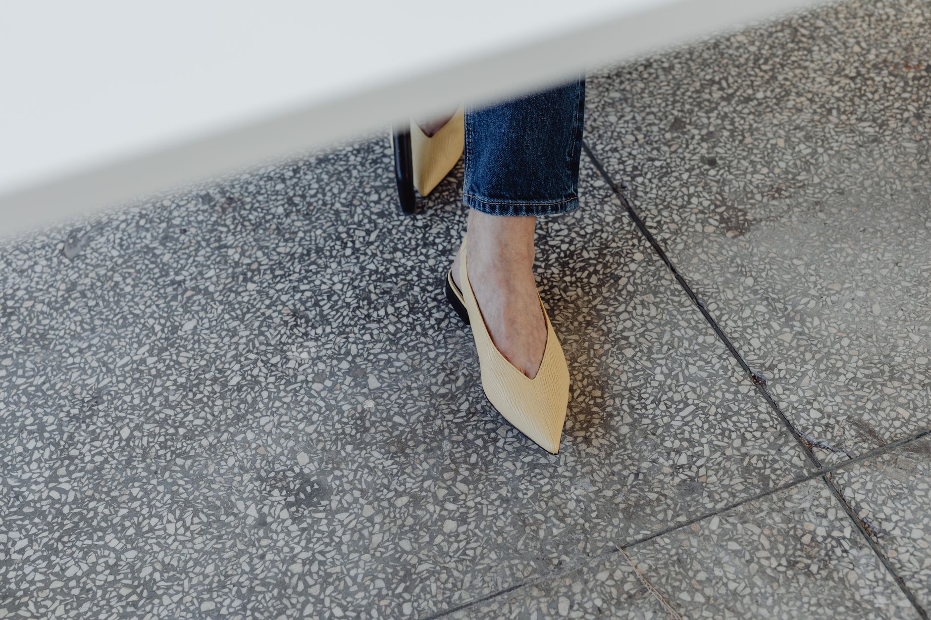 A pair of sleek pointed-toe flat shoes in neutral leather on a clean surface